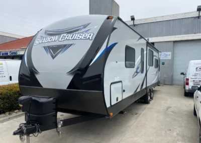A grey and black "Shadow Cruiser Ultra Lite" travel trailer parked on a paved surface.