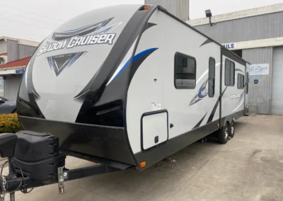 A Shadow Cruiser Ultra Lite RV parked outside a detailing shop with a clean and polished exterior.