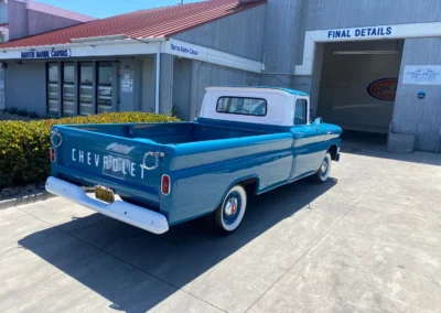 A restored vintage blue Chevrolet pickup truck parked outside Final Details detailing shop.