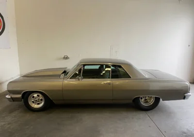 Classic gold/bronze Chevelle muscle car parked in white garage with custom wheels and lowered stance.