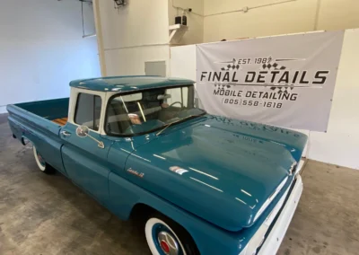 Classic blue Chevrolet Apache pickup truck with white roof in auto detailing shop, beautifully restored.