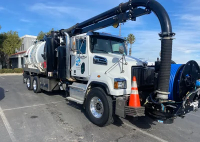 Industrial vacuum truck with large suction hose and tank for cleaning sewers/storm drains.